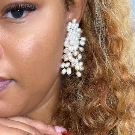 Close-up of a woman wearing pearl earrings with a blurred background